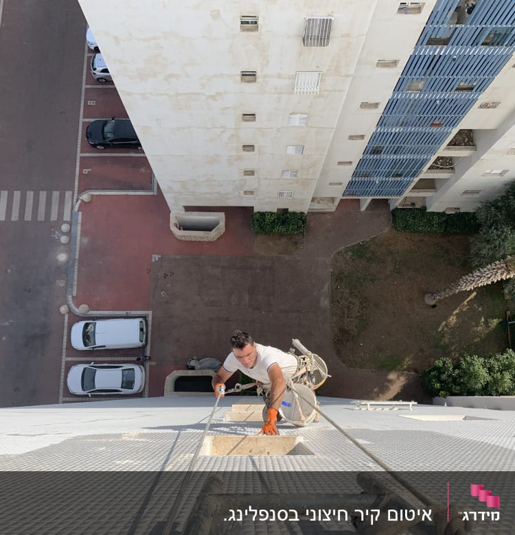 אדם מטפס על קיר בניין גבוה עם חבלים